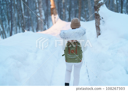 Woman tourist Visiting in Furano, Traveler in Sweater sightseeing Ningle Terrace Cottages with Snow in winter. landmark and popular for attractions in Hokkaido, Japan. Travel and Vacation concept 108267303
