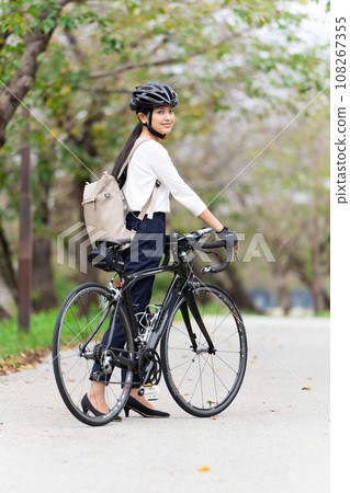 一位年輕女子穿著商務休閒服推著公路自行車行走，後視 108267355