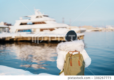 Woman tourist Visiting in Hakodate, Traveler in Sweater sightseeing Hakodate port near Red Brick Warehouse with Snow in winter. Hokkaido, Japan.Travel and Vacation concept 108267773