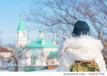 Woman tourist Visiting in Hakodate, Traveler in Sweater sightseeing Russian Orthodox Church with Snow in winter. landmark and popular for attractions in Hokkaido, Japan. Travel and Vacation concept 108267799