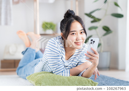 Young woman looking at her smartphone in the living room 108267963