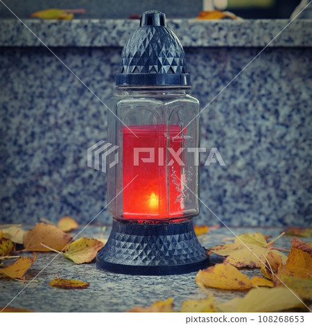 All Souls' Day. A lit candle on the grave. Background with cemetery. Autumn time and holidays. Soulstice - remembrance of the dead - Halloween holiday. 108268653