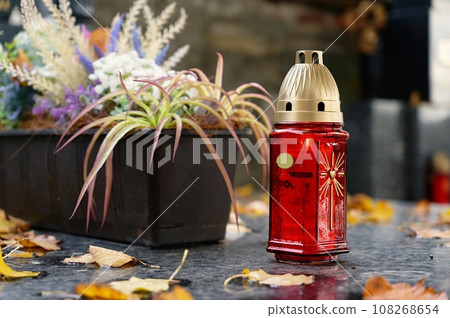 All Souls' Day. A lit candle on the grave. Background with cemetery. Autumn time and holidays. Soulstice - remembrance of the dead - Halloween holiday. 108268654