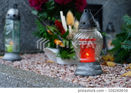 All Souls' Day. A lit candle on the grave. Background with cemetery. Autumn time and holidays. Soulstice - remembrance of the dead - Halloween holiday. All Souls' Day. A lit candle on the grave. Background with cemetery. Autumn time and holidays. Soulstice - remembrance of the dead - Halloween holiday. 108268656
