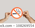 Closeup of woman hands showing card with no smoking sign, healthy lifestyle, healthy habits. Indoor studio shot isolated on gray background. 108269554