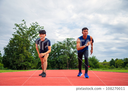 Two Teenagers Take starting pose for Running in lane Stadium 108270011
