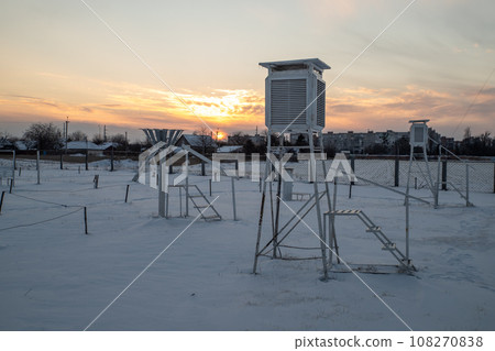 Weather station in the evening during sunset in winter. A device at a weather station for recording Weather station in the evening during sunset in winter. A device at a weather station for recording 108270838