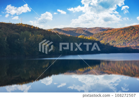 mountainous autumn landscape with lake. nature background with trees on the shore reflecting in the calm water. warm sunny weather in the morning 108272507