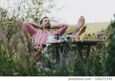 Relaxed man sitting in the garden with feet on table. Father having moment to himself while his kids are in school. Relaxed man sitting in the garden with feet on table. Father having moment to himself while his kids are in school. 108272543