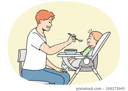 Young dad feeds baby sitting in highchair from spoon. 108273045