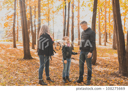 Family spend time in autumn park with a dog. Father, mother and daughter and jack russell terrier dog having fun in fall 108275669