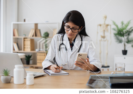 Female medic making consultation online using smartphone Female medic making consultation online using smartphone 108276325