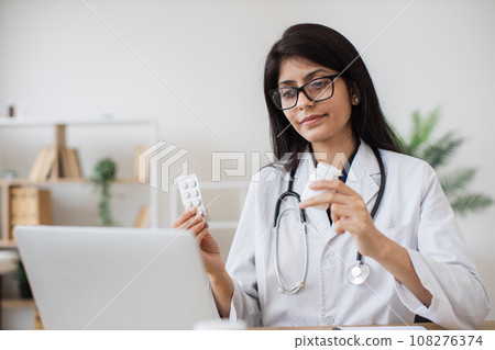 Hindu doctor consulting patient on video call in office 108276374