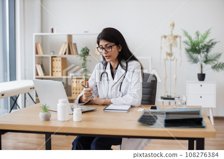 Female hindu physician having video conference in office Female hindu physician having video conference in office 108276384