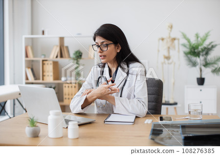 Female hindu physician having video conference in office Female hindu physician having video conference in office 108276385