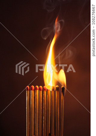 a row of matches are lit on a dark background 108276667