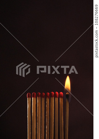 a row of matches are lit on a dark background 108276669
