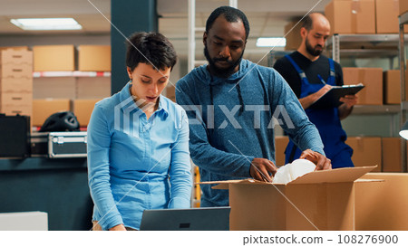 Team of owners doing highfive sign after packing order in box, preparing products to ship from storehourse. Young entrepreneurs checking supply chain and selling merchandise. Handheld shot. 108276900