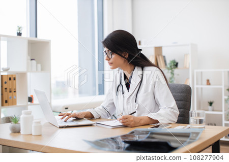 Doctor using computer while sitting at desk in health center 108277904