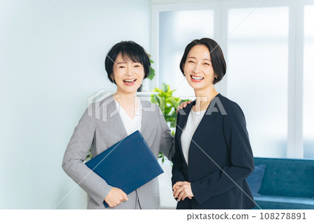 兩位女商人微笑著在辦公室排隊 兩位女商人微笑著在辦公室排隊 108278891