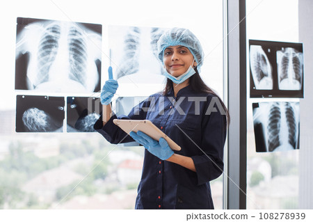Hindu surgeon with tablet standing near glass with xray scan 108278939