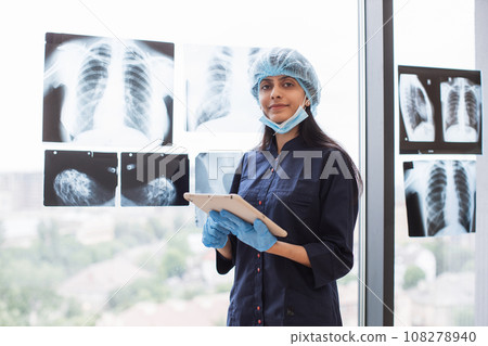 Hindu surgeon with tablet standing near glass with xray scan 108278940