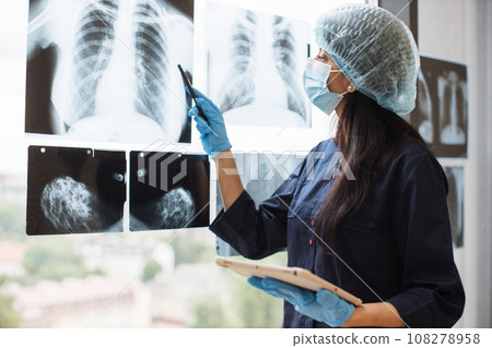 Female worker posing with digital tablet near x-ray scans Female worker posing with digital tablet near x-ray scans 108278958
