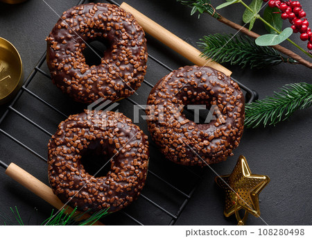 Chocolate donuts sprinkled with crushed nuts on a black table Chocolate donuts sprinkled with crushed nuts on a black table 108280498