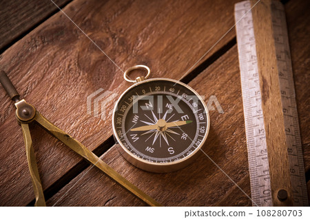 Vintage rule, drawing and navigational Compass on a rustic wooden board Vintage rule, drawing and navigational Compass on a rustic wooden board 108280703