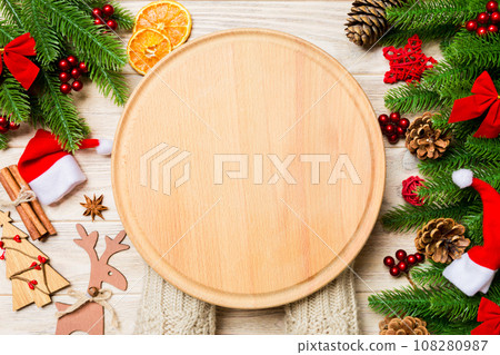 Top view of female hand holding a plate on holiday wooden background. Fir tree and Christmas decorations. New Year time cocnept Top view of female hand holding a plate on holiday wooden background. Fir tree and Christmas decorations. New Year time cocnept 108280987