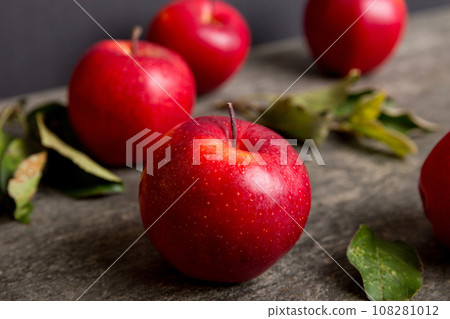 Fresh red apples with green leaves on wooden table. On wooden background. Top view free space for text 108281012