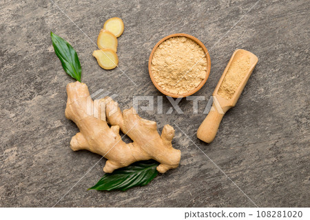 Finely dry Ginger powder in bowl with green leaves isolated on colored background. top view flat lay Finely dry Ginger powder in bowl with green leaves isolated on colored background. top view flat lay 108281020