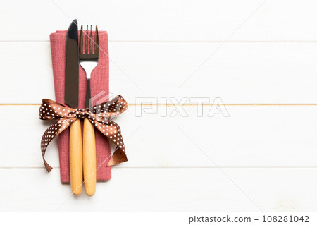 Top view of fork and knife on napkin on wooden background. Different christmas decorations and toys. New Year dinner concept with empty space for your design 108281042