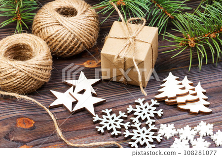 Christmas decoration, gift box in craft paper with twine rope, concept background, top view on wood table surface. Christmas ornaments and presents border with snowflakes and stars Christmas decoration, gift box in craft paper with twine rope, concept background, top view on wood table surface. Christmas ornaments and presents border with snowflakes and stars 108281077