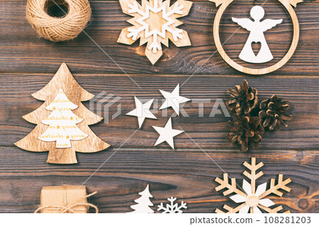Christmas composition. Christmas snowflakes, Christmas tree and angel in a frame on a wooden background. New Year wooden decorations. Toned 108281203