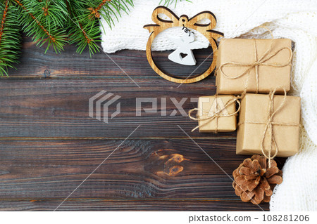 Christmas decoration, gift boxes and angel figure frame background, top view with copy space on white wood table surface. Christmas ornaments and presents border 108281206