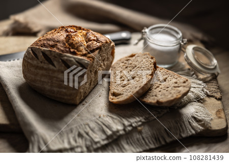 Fresh sourdough bread with a cut slice and salt on a cutting board Fresh sourdough bread with a cut slice and salt on a cutting board 108281439