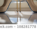 Elegant white bridal heels and wedding ring on a reflective surface, with a luxuriously blurred room backdrop. 108281778