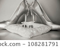 Elegant white bridal heels and wedding ring on a reflective surface, with a luxuriously blurred room backdrop. 108281791