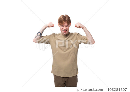 young well-groomed caucasian man with red hair is dressed in a khaki shirt and brown trousers on a young well-groomed caucasian man with red hair is dressed in a khaki shirt and brown trousers on a 108281807