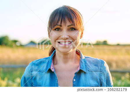 Portrait of smiling middle aged woman looking at camera, summer countryside 108282179