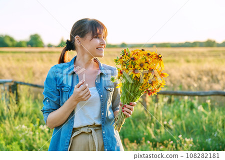 Profile view, happy middle aged woman with flowers looking at setting sun 108282181