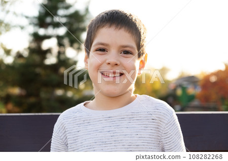 Portrait of a smiling six-year-old boy in an autumn park. Happy childhood Portrait of a smiling six-year-old boy in an autumn park. Happy childhood 108282268
