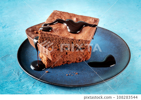 Chocolate brownie with syrup sauce, simple coffee cake, on blue Chocolate brownie with syrup sauce, simple coffee cake, on blue 108283544
