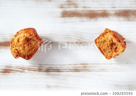 Broken orange muffins on a rustic wooden kitchen table, overhead flat lay Broken orange muffins on a rustic wooden kitchen table, overhead flat lay 108283593
