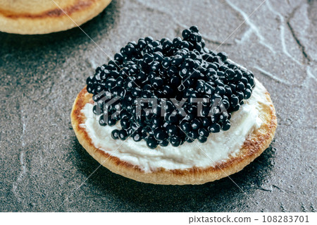 A blini with caviar and cream cheese, a closeup on black 108283701