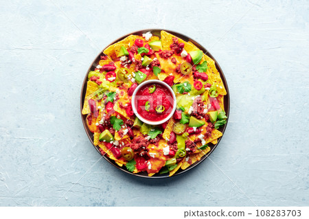 Loaded nachos. Mexican nacho chips with beef and guacamole sauce 108283703