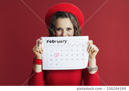 stylish woman in red dress and beret with February calendar 108284169