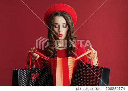 surprised stylish woman in dress and beret with shopping bags 108284174