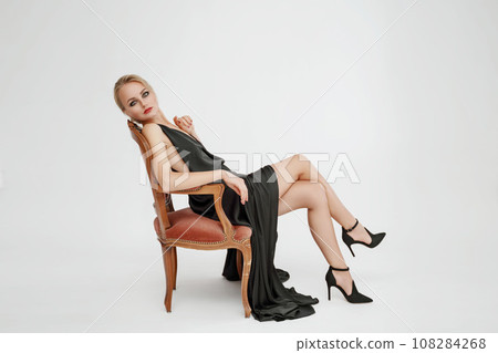 Woman in black dress on white background in the studio. Elegant lady in long gown. Sexy girl in formal prom dress. Woman in black dress on white background in the studio. Elegant lady in long gown. Sexy girl in formal prom dress. 108284268